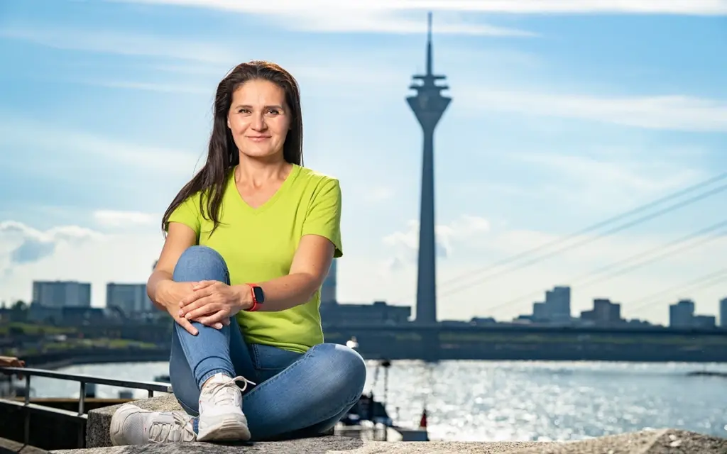 Was kostet Personal Training in Düsseldorf - Magdalena Stramput sitzt an den Kasematten in Düsseldorf mit Rheinturm im Hintergrund